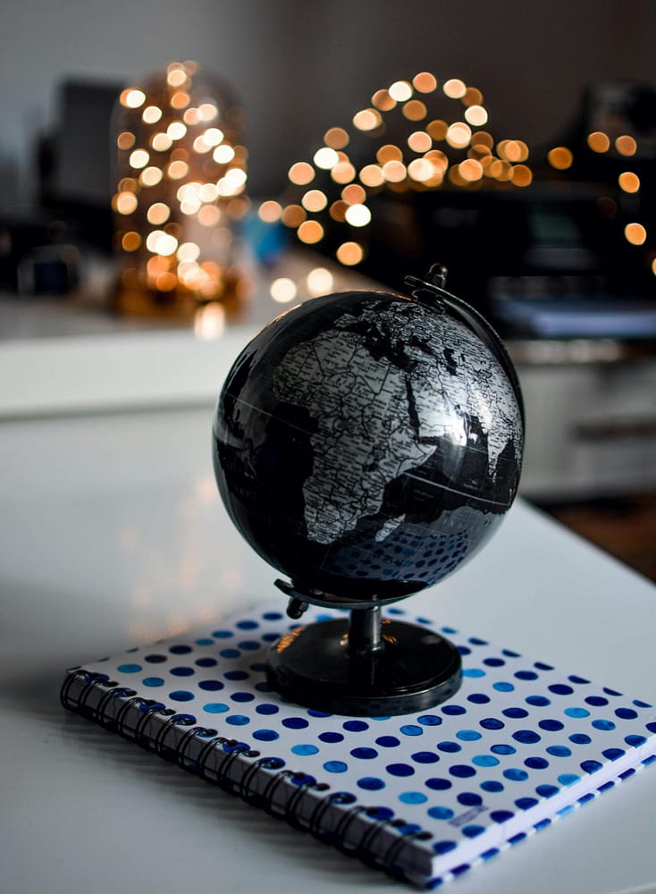 pexels-photo-1236421-1236421 Elegant black globe and notebook against warm bokeh lights, perfect for educational themes.