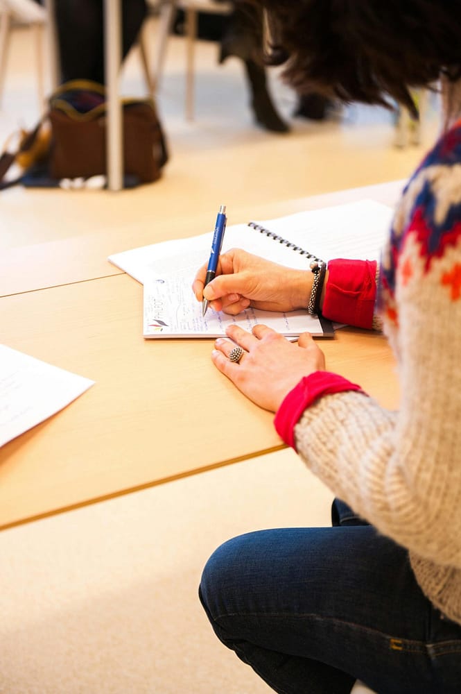 pexels-photo-261651-261651 A woman writing notes in a notebook during a classroom lecture setting.